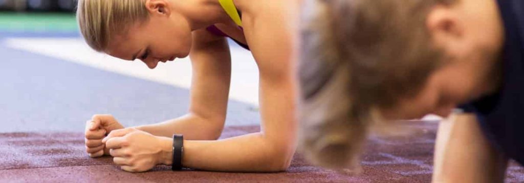 woman and man doing plank exercise in gym